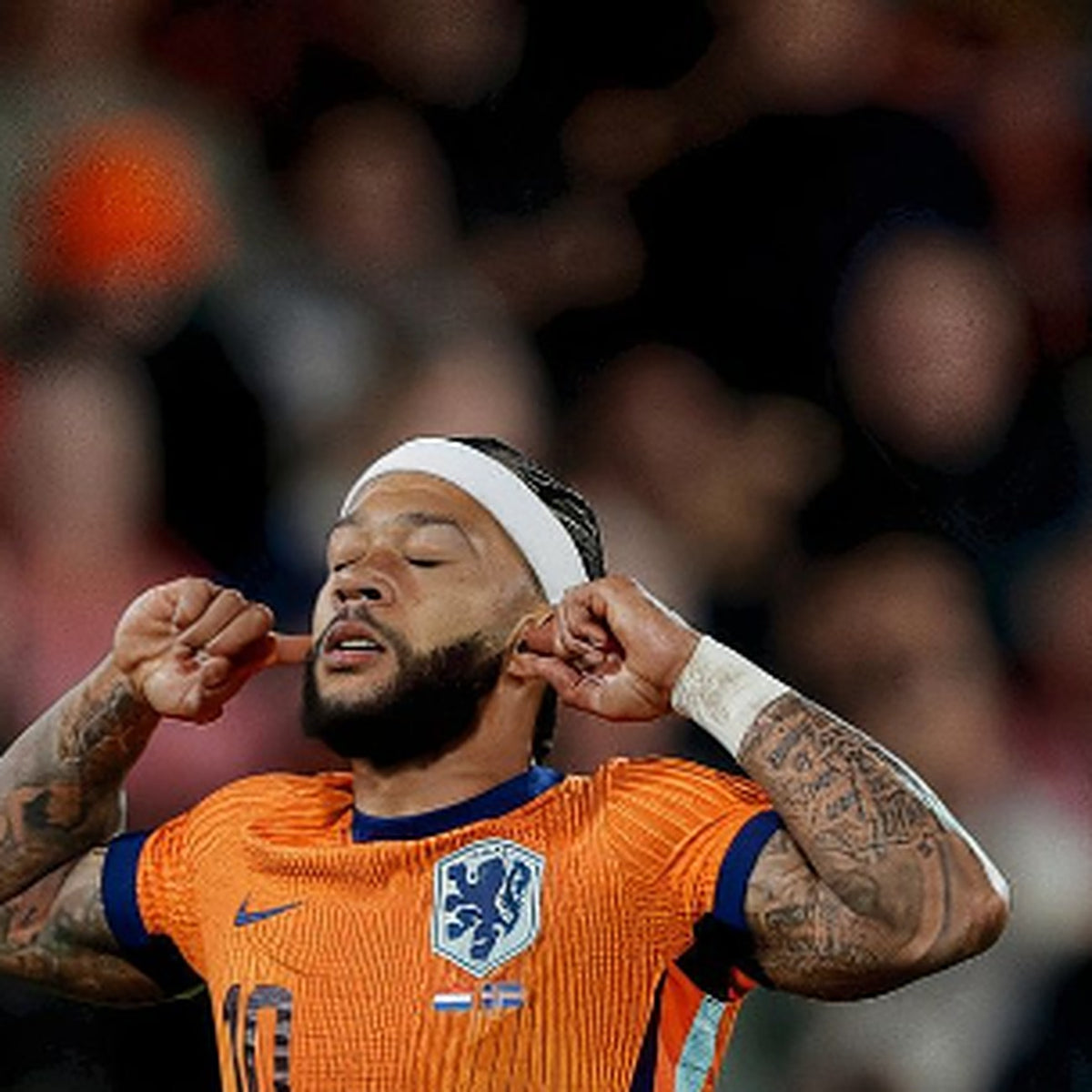 Memphis Depay in het oranje shirt van het Nederlands elftal, met zijn vingers in zijn oren